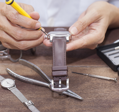 Man with watch repair tools removing back of watch