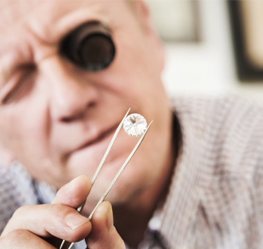 Man with magnifying lens, assessing diamond