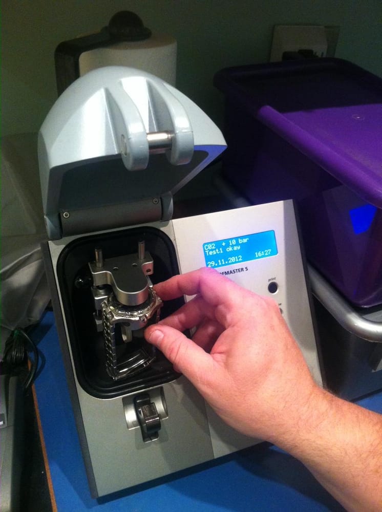 A hand holding a watch to complete a Watch Leak and Pressure Test