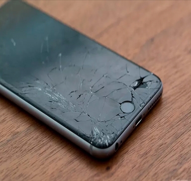 Cracked black iphone on wooden surface