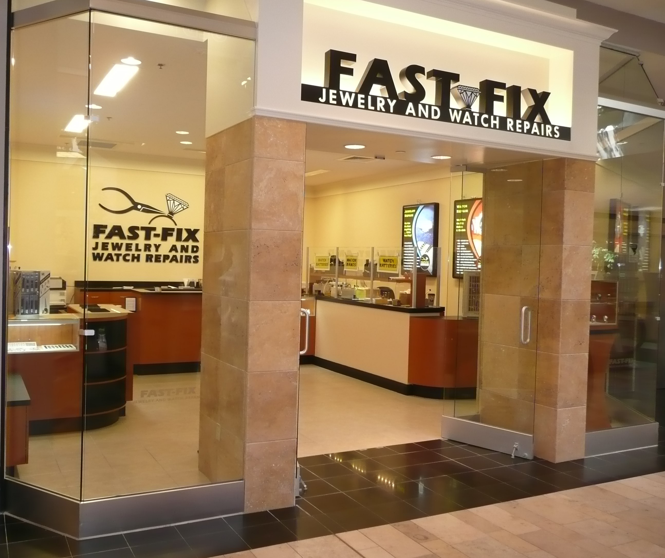 Outside view of store showing front glass, stone-faced pillars, and overhead signage