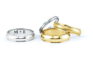 Four wedding bands, 2 gold and 2 platinum. One shows an engraved sentence: M+E